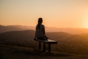 woman relaxing by sunset to reduce stress