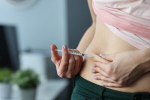 woman giving herself a weight loss injection shot in stomach